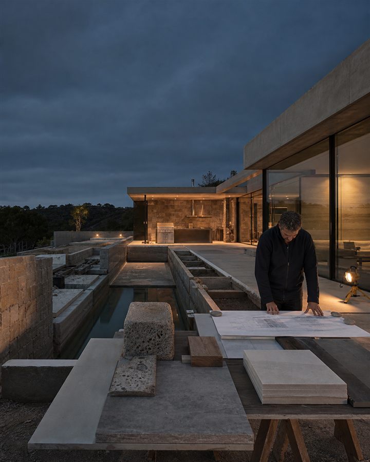 Illustrative design-build lead reviewing plans beside a premium outdoor project
